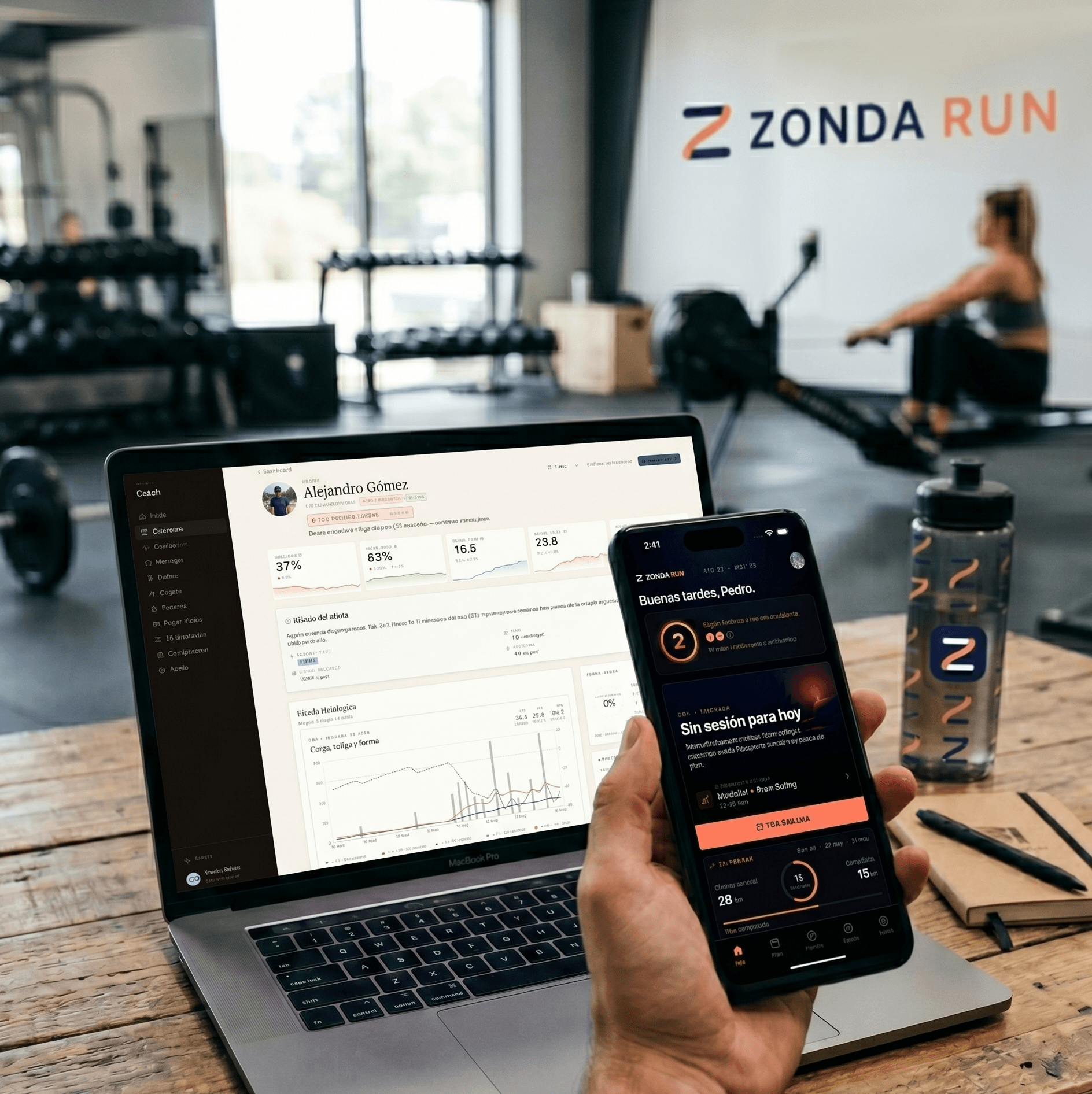 Coach revisando el dashboard de Zonda en su laptop mientras un atleta sigue su plan de entrenamiento desde la app móvil, en un gimnasio de cross-training.
