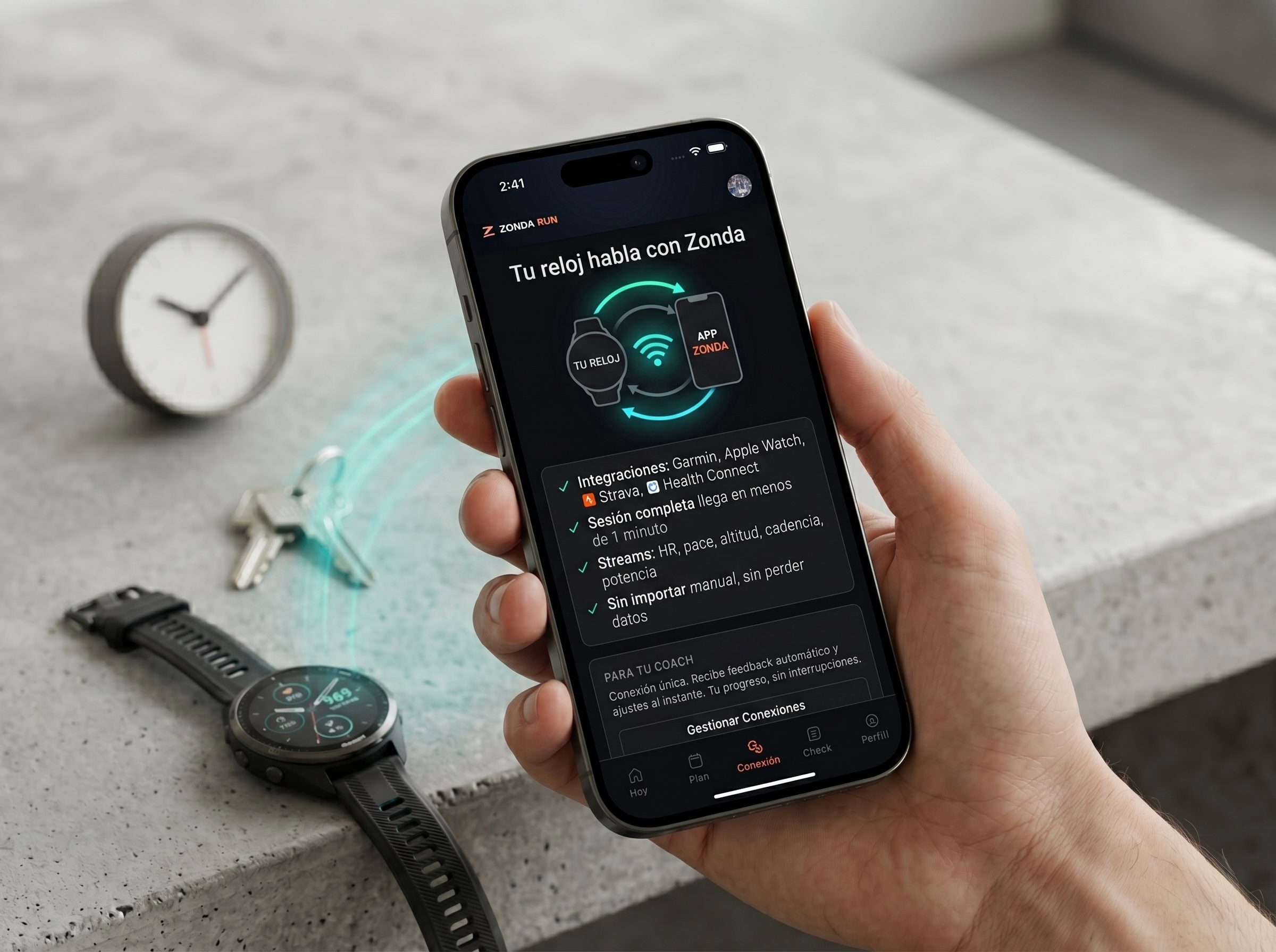 Mano sosteniendo un iPhone con la app de Zonda Run mostrando 'Tu reloj habla con Zonda', con las integraciones Garmin, Apple Watch, Strava y Health Connect, junto a un reloj GPS real apoyado sobre concreto.